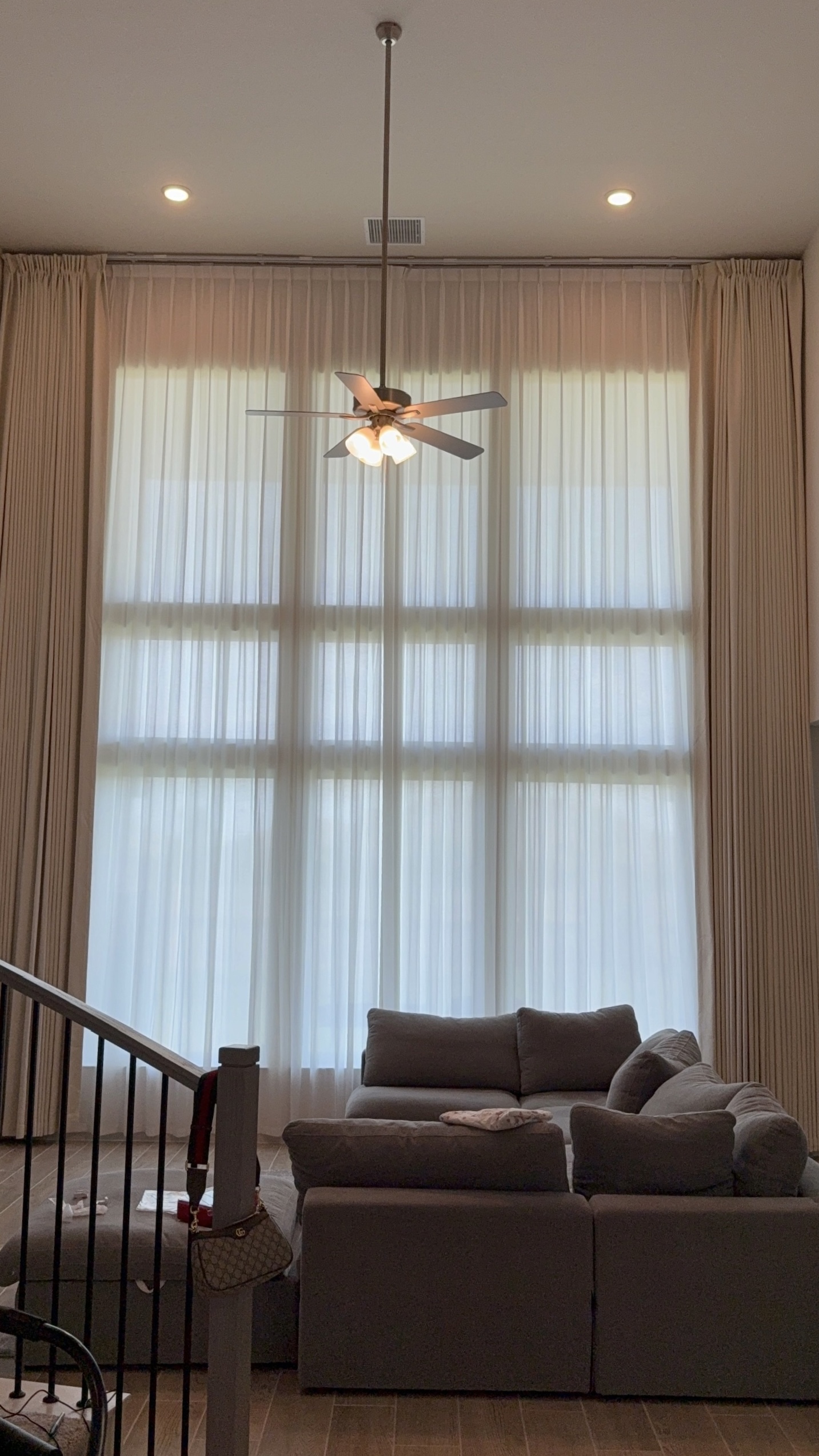 Soaring windows framed by neutral drapery and layered zebra shades